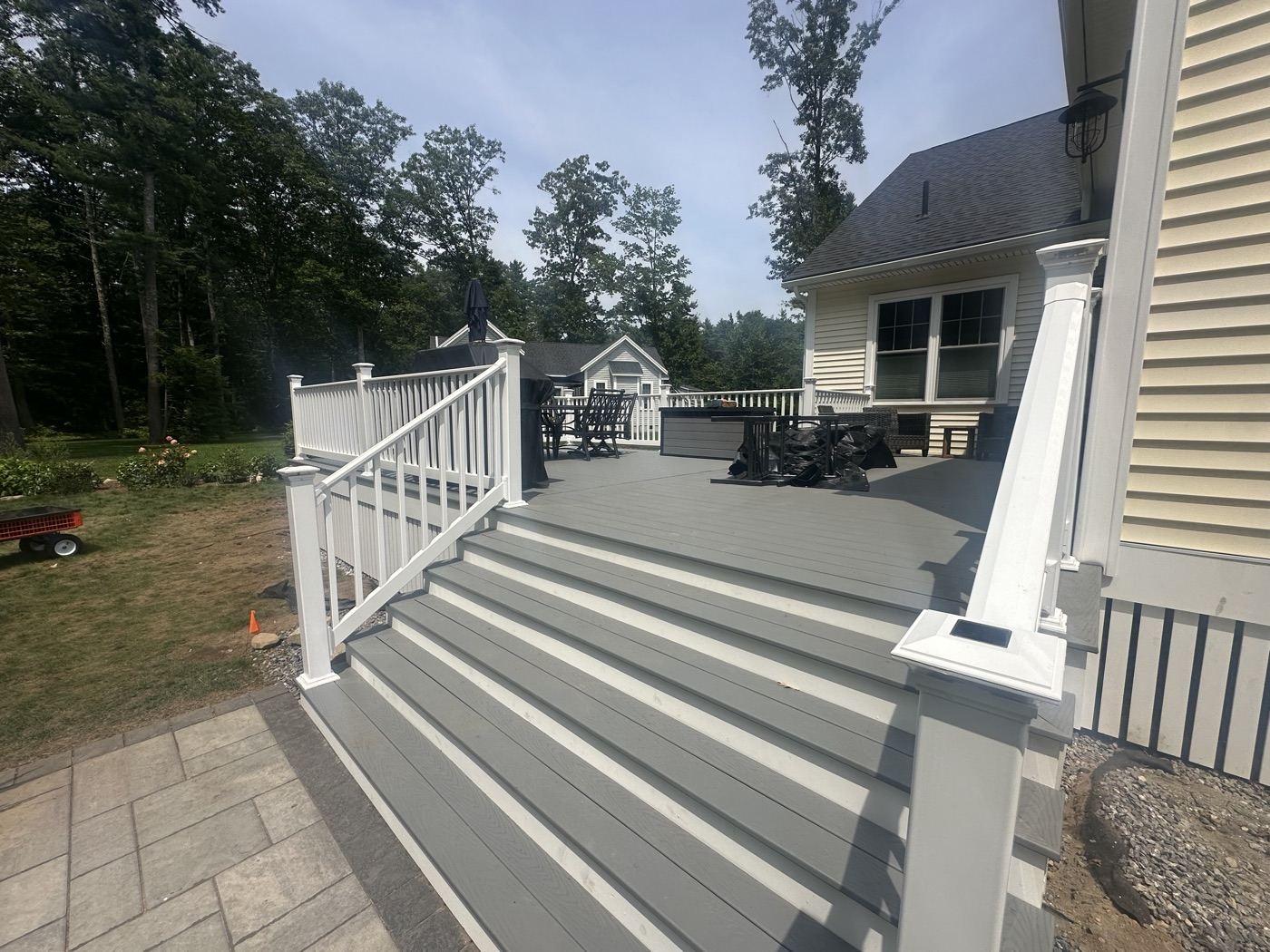 Stairs running from the composite deck down to the paver patio in Wells, Maine