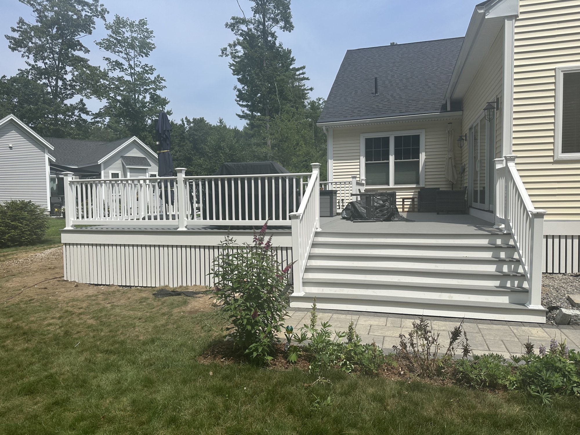 Composite deck and paver walkway behind a finished home in Wells, Maine
