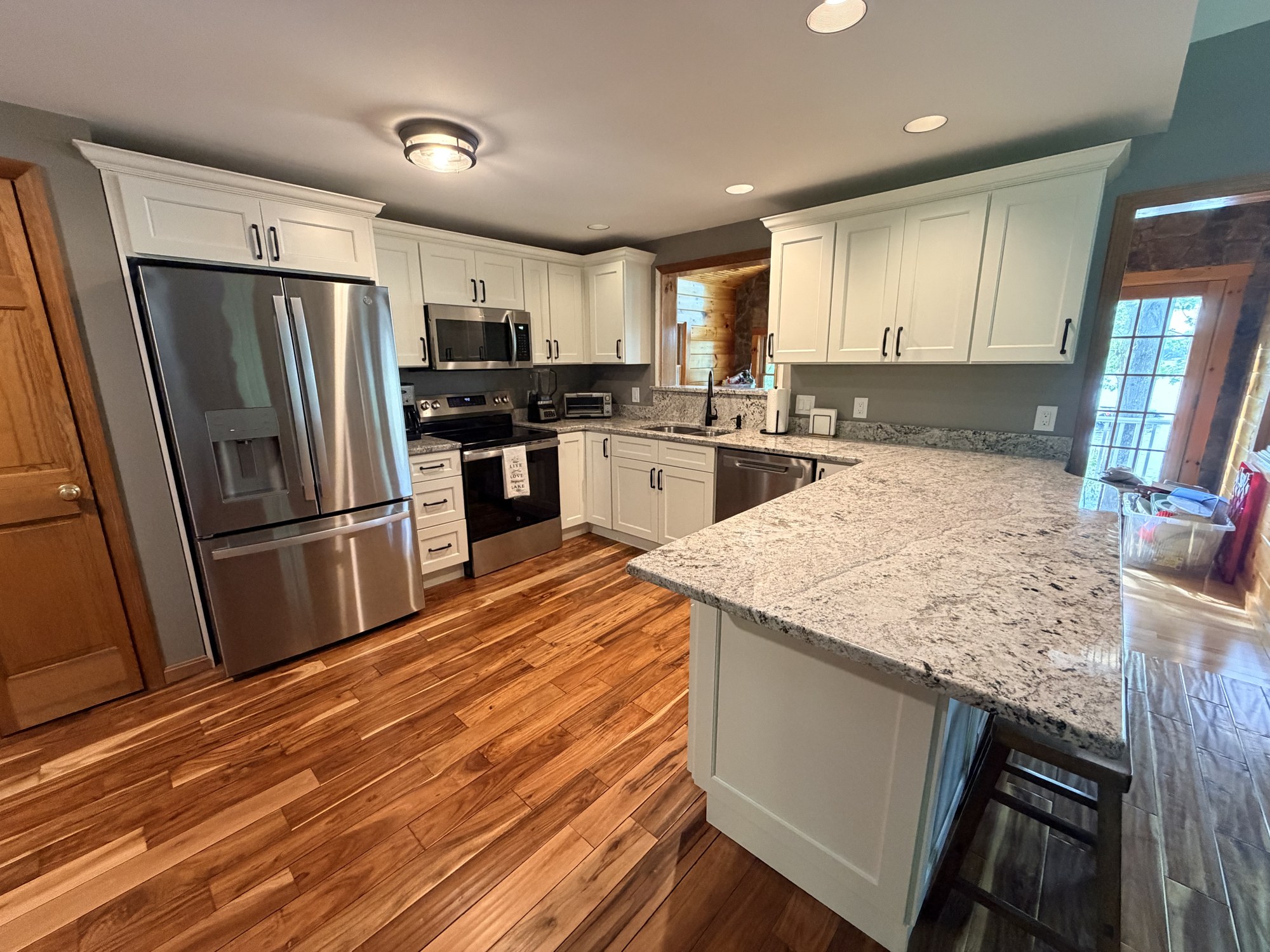 White shaker kitchen with granite counters and a stainless refrigerator