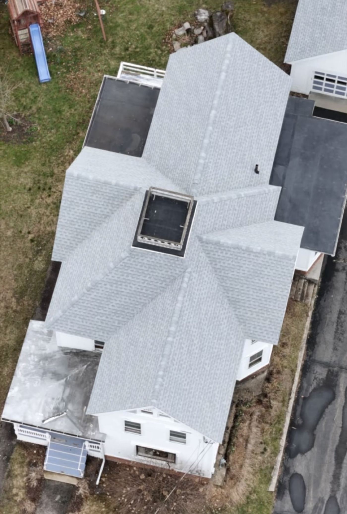 Aerial view of a completed gray shingle roof on a hip-roofed house